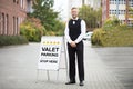 Young Male Valet Standing Near Valet Parking Sign