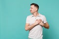 Portrait of smiling young man in casual clothes looking aside, holding hands on heart, chest isolated on blue turquoise Royalty Free Stock Photo