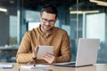 Portrait of a smiling young man designer, engineer, architect sitting in the office behind a notebook and works, draws Royalty Free Stock Photo