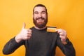 Portrait of smiling young man holding credit card and showing thumb up Royalty Free Stock Photo