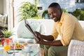 Portrait of smiling young man holding newspaper by breakfast table at cafe Royalty Free Stock Photo