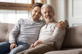 Portrait smiling young man hugging mature father, sitting on couch Royalty Free Stock Photo