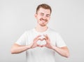 Portrait of smiling young man keeps hands on chest in heart shape sign, expresses sympathy