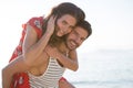 Portrait of smiling young man piggybacking his girlfriend at beach Royalty Free Stock Photo