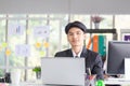 Portrait of smiling young man sitting at his desk in the office, Businessman in suit working with laptop in office Royalty Free Stock Photo