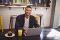 Portrait of smiling young man sitting with laptop at coffee shop Royalty Free Stock Photo