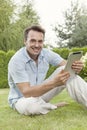 Portrait of smiling young man using tablet computer in park Royalty Free Stock Photo