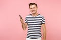 Portrait of smiling young man wearing striped t-shirt listening music with white earphones in mobile phone, enjoy Royalty Free Stock Photo