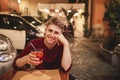 Portrait of a smiling young man who sits in the evening in a restaurant with a glass of alcohol in his hands