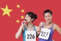 Portrait of smiling young medalists standing against Chinese flag Royalty Free Stock Photo