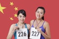 Portrait of smiling young medalists standing against Chinese flag Royalty Free Stock Photo