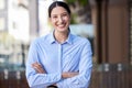 Portrait of a smiling young mixed race woman standing with her arms crossed outdoors. Young happy hispanic female Royalty Free Stock Photo