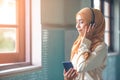 Portrait of a smiling young modern arabian woman closing eyes, holding mobile phone and listening the music to headphone Royalty Free Stock Photo