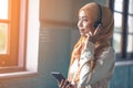 Portrait of a smiling young modern arabian woman holding mobile phone and listening the music to headphone Royalty Free Stock Photo