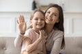 Happy mom and little daughter look at camera waving