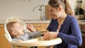 Portrait of smiling young mother feeding her baby son with fruit porridge. Concept of parenting, healthy nutrition and baby care Royalty Free Stock Photo