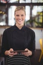 Portrait of smiling young pretty waitress holding digital tablet Royalty Free Stock Photo