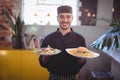 Portrait of smiling young waiter serving fresh food Royalty Free Stock Photo