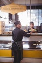 Portrait of smiling young waiter and waitress holding plates at counter Royalty Free Stock Photo