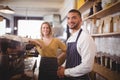 Portrait of smiling young waiter and waitress standing by espresso maker Royalty Free Stock Photo