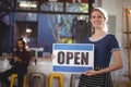 Portrait of smiling young waitress holding open sign placard Royalty Free Stock Photo