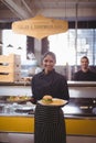 Portrait of smiling young waitress serving food while standing against waiter Royalty Free Stock Photo