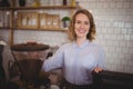 Portrait of smiling young waitress standing by coffee maker Royalty Free Stock Photo