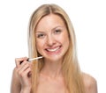 Portrait of smiling young woman applying lip gloss Royalty Free Stock Photo