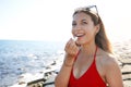 Portrait of smiling young woman applying sun protection on her lip on the beach Royalty Free Stock Photo