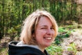 Portrait of a smiling young woman with blonde hair in a coniferous forest in early spring Royalty Free Stock Photo