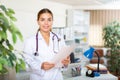 Smiling woman doctor standing in office with papers in hands Royalty Free Stock Photo