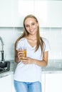 Portrait of a smiling young woman drinking orange juice in the kitchen at home Royalty Free Stock Photo