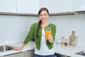 Portrait of a smiling young woman drinking orange juice in the kitchen at home Royalty Free Stock Photo