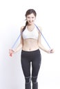 Portrait of smiling young woman exercising with skipping rope against white background Royalty Free Stock Photo