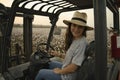 Portrait of smiling young woman farmer sitting on small farm tractor Royalty Free Stock Photo