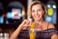 A portrait of smiling young woman with glass of mango juice on the table in cafe. People and lifestyle concept