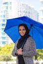 Portrait of smiling young woman holding big blue umbrella Royalty Free Stock Photo