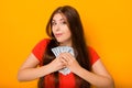 Portrait of a smiling young woman holding a bunch of money banknotes in hands isolated on a yellow background. Royalty Free Stock Photo