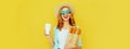 Portrait of smiling young woman holding grocery shopping paper bag with long white bread baguette and coffee cup on yellow Royalty Free Stock Photo