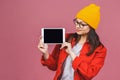 Portrait of smiling young woman holding in her hands a digital tablet with blank screen while standing over isolated pink Royalty Free Stock Photo