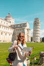 Portrait of smiling young woman with map in front in front of leaning tower of pisa, tuscany, italy Royalty Free Stock Photo