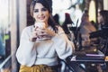 Portrait of smiling young woman with paper cup of coffee in her hands,sitting at table in cafe,looking at camera. Lifestyle Royalty Free Stock Photo