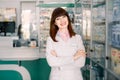 Portrait of a smiling young woman pharmacist with arms crossed at modern pharmacy. Beautiful woman wearing in white lab Royalty Free Stock Photo