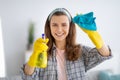 Portrait of smiling young woman in rubber gloves cleaning glass with spray detergent, indoors Royalty Free Stock Photo