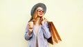 Portrait smiling young woman with shopping bags, holding coffee cup, wearing pink coat, round hat on background Royalty Free Stock Photo