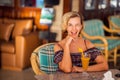 A portrait of smiling young woman with glass of mango juice on the table in cafe. People and lifestyle concept