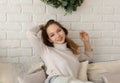 Portrait of smiling young woman sitting in the chair and looking at camera on the white brick wall background Royalty Free Stock Photo