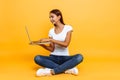 Young woman sitting cross-legged using laptop isolated on yellow background Royalty Free Stock Photo