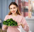 Portrait of a positive young woman with a plate of spinach