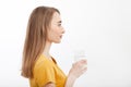 Portrait of smiling young woman standing in profile and holding a glass of water. white background. mock up. Fashion Royalty Free Stock Photo